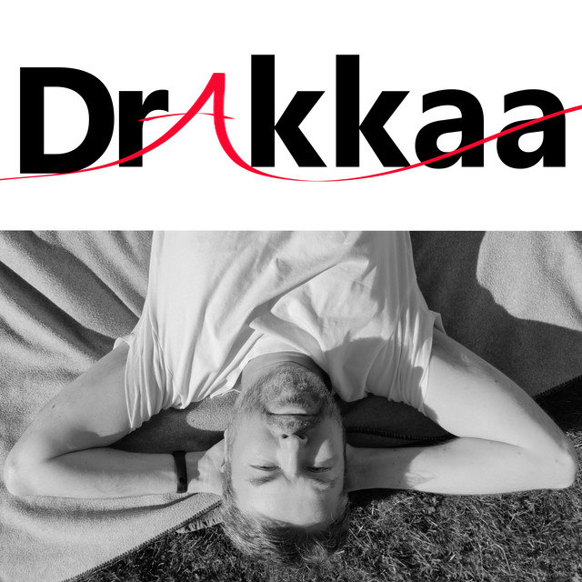 Drakkaa lying on the grass, eyes closed, photographed upside down in black and white